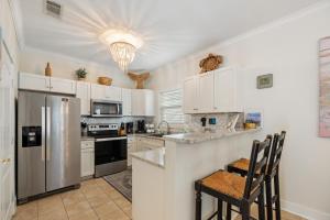 a kitchen with white cabinets and a stainless steel refrigerator at Captain's Chair 18A By Pkrm in Pensacola
