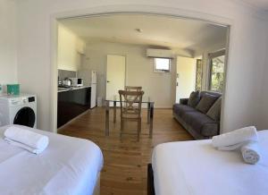 a room with two beds and a living room with a couch at Studio house Unit in Dundas Valley in Sydney +1 photo