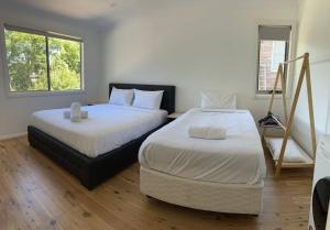 a bedroom with two beds and two windows at Studio house Unit in Dundas Valley in Sydney