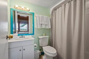 a bathroom with a toilet and a sink and a mirror at Oceanfront Inn Room #7 - Partial Ocean View - King Bed in Fort Pierce