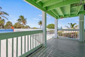 a porch with a view of the beach and palm trees at Oceanfront Inn Room #7 - Partial Ocean View - King Bed in Fort Pierce