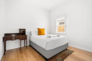 a white bedroom with a bed and a table at Emu Nest at East Geelong in Thomson +5 photos