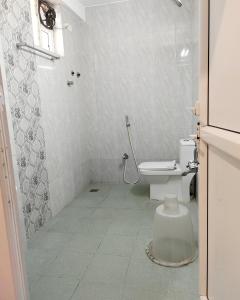 a white bathroom with a toilet and a shower at Serenity Sands Beach Resort in Puducherry