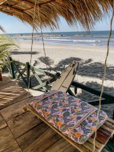 a surfboard hanging from a straw umbrella on a beach at Nimbu Beachhouse in Transito +78 photos