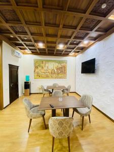 ein Zimmer mit einem Tisch, Stühlen und einem Gemälde in der Unterkunft Orbita Villa boutique in Buxoro