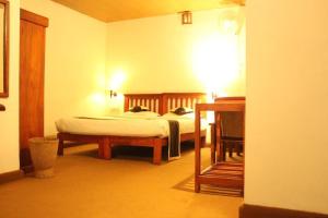 a bedroom with a bed and a desk in a room at Glenmore Resorts Munnar in Anachal