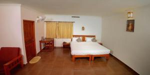 a bedroom with a white bed and a wooden floor at Glenmore Resorts Munnar in Anachal