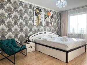 a bedroom with a bed and a green chair at Апартаменты стандарт in Pavlodar