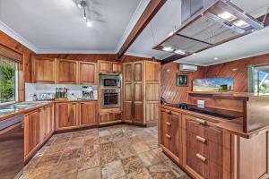 a kitchen with wooden cabinets and a large island at Treetop Paradise Retreat with Pool in Cannonvale