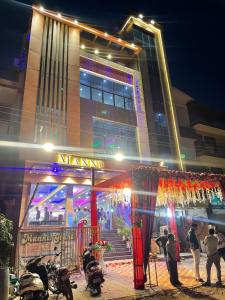 坎普尔Hotel Mannu Grand的一座建筑,人们在晚上站在外面