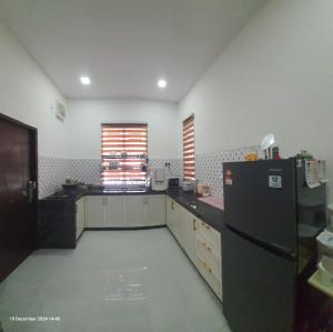 a kitchen with a black refrigerator and a window at Homestay Cheq Gu 747 in Ayer Hitam