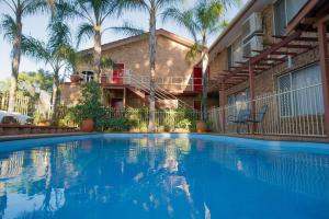 a swimming pool in front of a building with palm trees at Manera Heights Apartments in Dubbo
