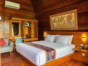 a bedroom with a large white bed and a chair at Adil Villa & Resort in Ubud