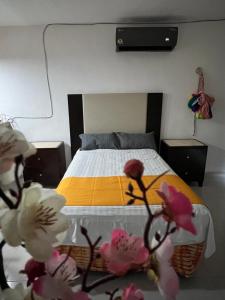 a bedroom with a bed and flowers in the foreground at departamento sisal 1 in Valladolid