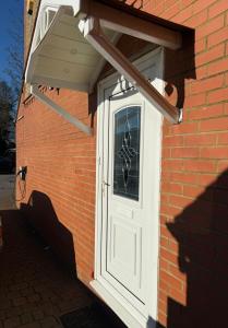 a white door on the side of a brick building at PRIME LOCATION Luton home - FREE PARKING in Luton