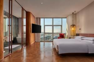Un dormitorio con una gran cama blanca y un televisor. en Mumian Beijing Daxing International Airport, part of Hyatt, en Beijing