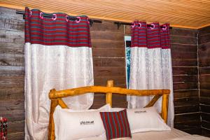 a bedroom with a bed and two curtains at Eliata Bush Camp in Kajiado +4 photos