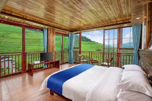 a bedroom with a bed and a balcony with windows at Longji Forest Lodge--Terraced landscape from the room, Pick-up and drop-off service from Ping'an Village Parking Lot, Sunrise& Sunset in Heping
