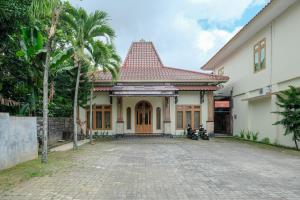 a house with a cobblestone driveway in front of it at RedDoorz at Savitri Hotel in Yogyakarta