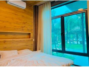 a bedroom with a bed and a large window at BIRD HOUSE resort in Hữu Biêt