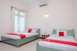 a bedroom with two beds and a window at RedDoorz at Savitri Hotel in Yogyakarta