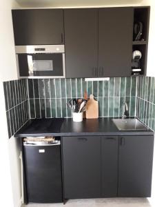 a black kitchen with a sink and a stove at A 300m de la plage, appartement moderne et cosy in Merville-Franceville-Plage +9 photos