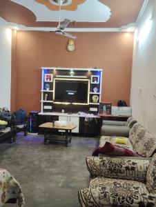 a living room with couches and a flat screen tv at Chauhans house in Prayagraj