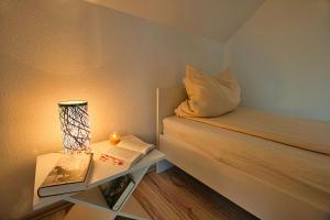 Cette petite chambre comprend un lit avec une lampe et un livre. dans l'établissement Auerhahn Ferienhäuser Auerhahn 403, à Hahnenkopf