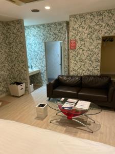 ein Wohnzimmer mit Ledersofa und Glastisch in der Unterkunft Elk in Kubota