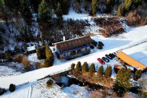 a building in the snow with cars parked in front at Agrorelax in Veľký Lipník