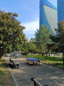 un parco con panchine e un tavolo da ping pong di Sea view Apartments in Orbi City a Batumi