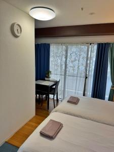 a bedroom with two beds and a table and a clock at Uhome Ueno Hotel in Tokyo