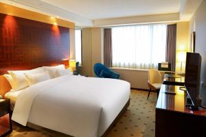 a hotel room with a large white bed and a desk at Radisson Collection Hyland Shanghai in Shanghai