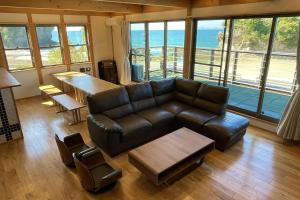 萨摩川内市Nishikata Beach House 1 -西方海岸貸別荘 壱号-的配有皮沙发和桌子的客厅