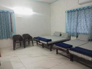 a room with three beds and chairs in it at DWARKA TOURIST BUNGALOW Only Family in Dwarka +16 photos