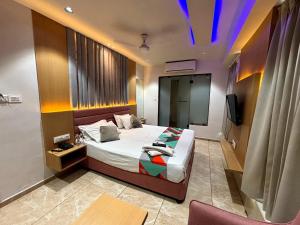 a bedroom with a bed and a tv in it at Hotel Cozzy Palace in Surat