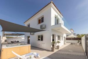 a white house with an outdoor kitchen and an umbrella at Villa Antonieta in Ayia Napa
