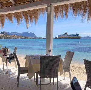 Guest House Via Acquedotto Romano في أولبيا: طاولة وكراسي على الشاطئ مع سفينة سياحية