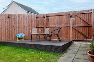 two chairs and a table on a deck next to a fence at 3 Bedroom House-Private Parking in Bonnyrigg
