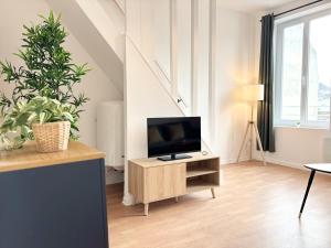 a living room with a tv on a wooden stand at Duplex rénové pour 6 voyageurs - Roubaix in Roubaix +8 photos