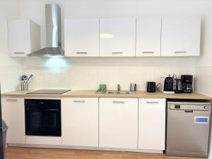 a white kitchen with white cabinets and a sink at Duplex rénové pour 6 voyageurs - Roubaix in Roubaix