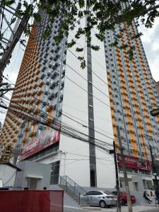 un edificio alto con un coche aparcado delante de él en Condo in Cubao by Cindy, en Manila