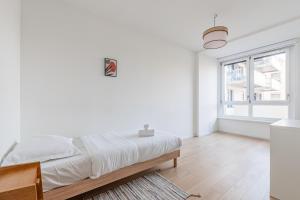 a white bedroom with a bed and a window at L'Académie - Magnifique 3 chambres Krutenau avec parking in Strasbourg