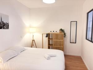 - une chambre blanche avec un lit et une lampe dans l'établissement Grand appartement avec terrasse - 4 voyageurs, à Roubaix
