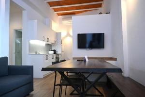 a living room with a table and a tv on a wall at Homenfun Dalt Badalona in Badalona