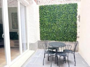 une table et des chaises sur une terrasse avec une haie verte dans l'établissement Grand appartement avec terrasse - 4 voyageurs, à Roubaix