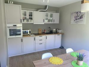 a kitchen with white cabinets and a wooden table at Kopli puhkemaja Saaremaal in Kasti