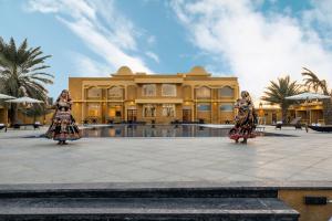 two women in skirts standing in front of a building at Sterling Rudraksh Jaisalmer in Jaisalmer