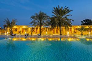 a large swimming pool in front of a building with palm trees at Sterling Rudraksh Jaisalmer in Jaisalmer