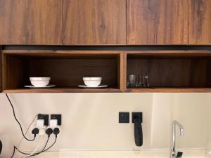 a kitchen with wooden cabinets with cups and plates on a shelf at Studio Sulimaniyah in Riyadh